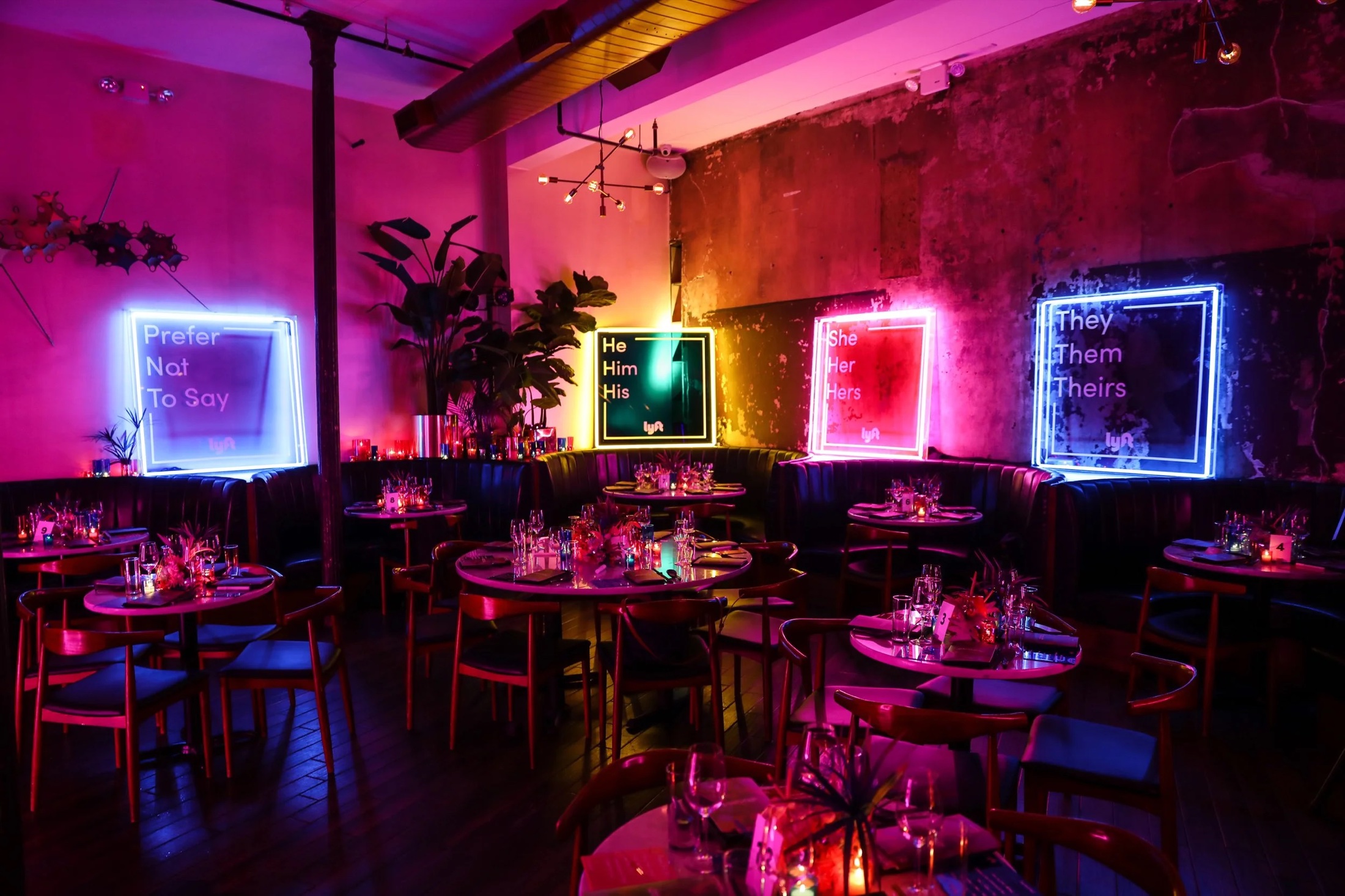 A dinner set under neon light boxes in a brick loft