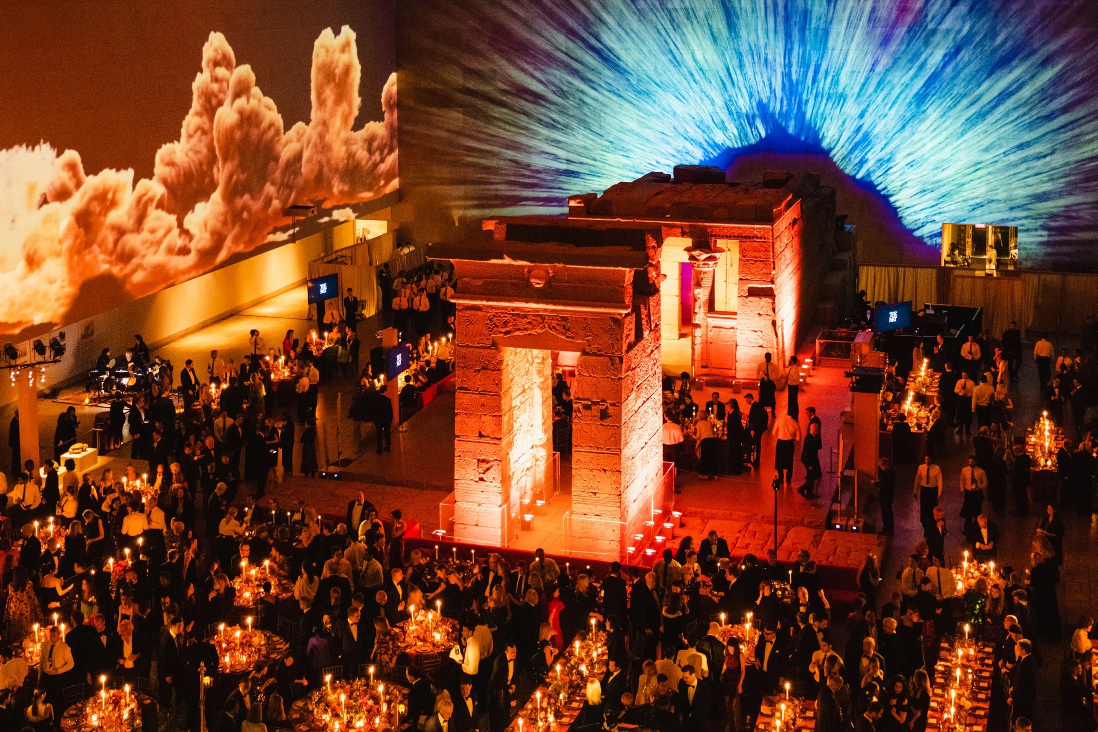 An ancient temple lit for a gala under a sky of projected light