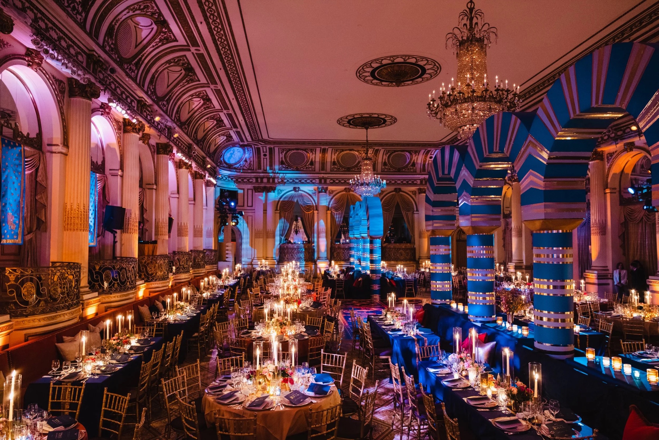 A gilded ballroom set for a seated gala dinner