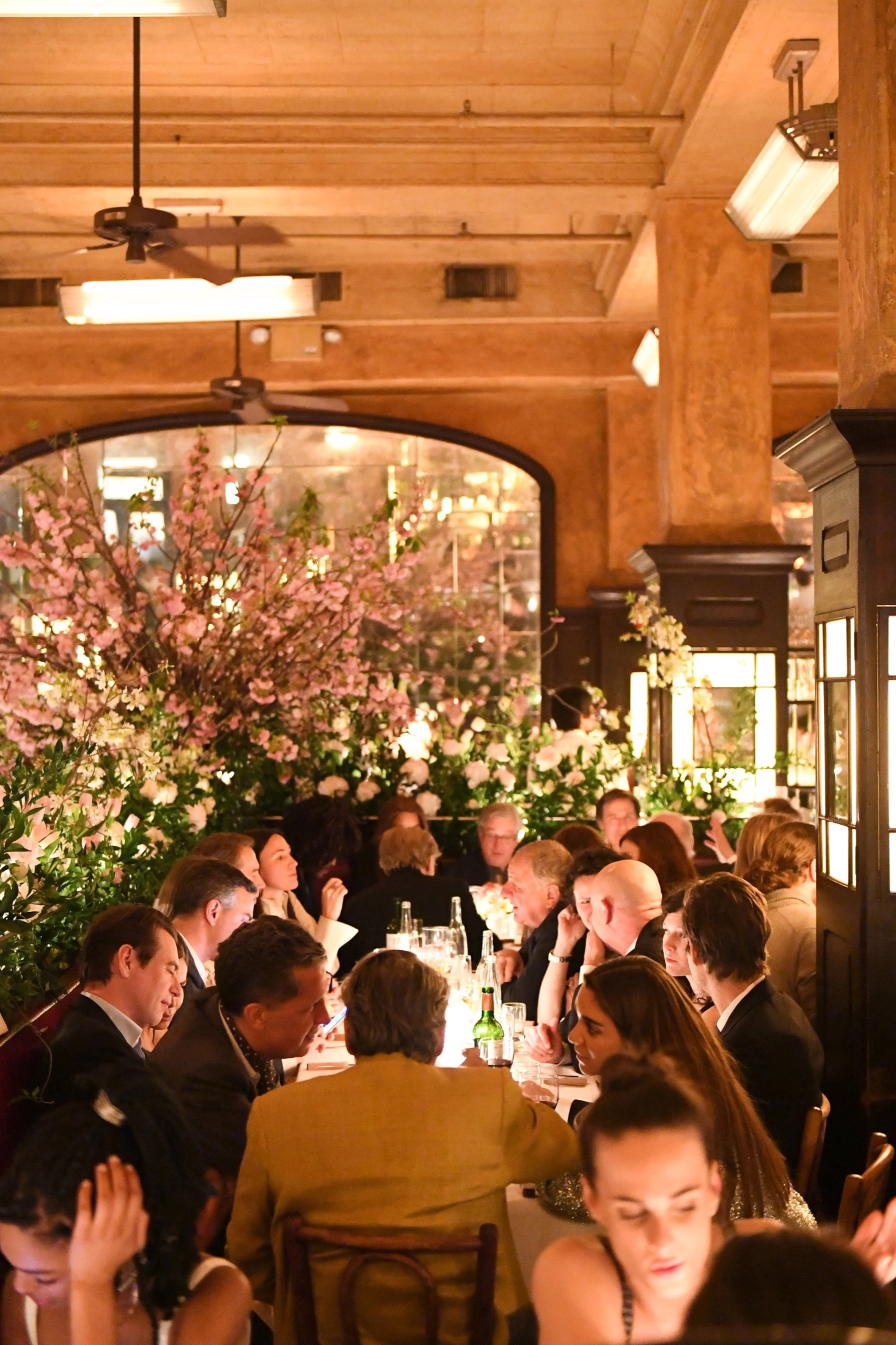 A dinner under a canopy of pink blossom in a grand room
