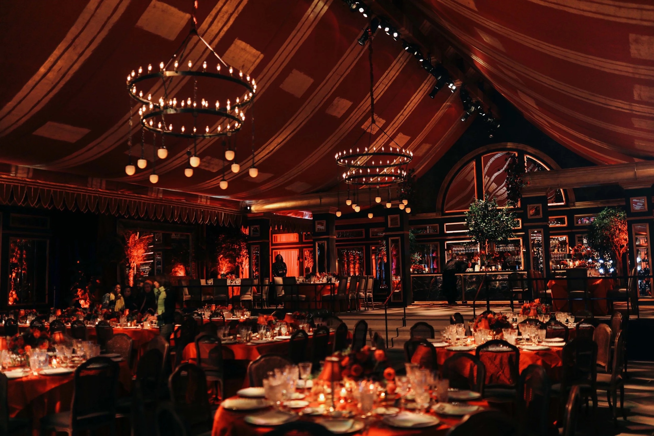 A candlelit dinner under chandeliers in a brick hall