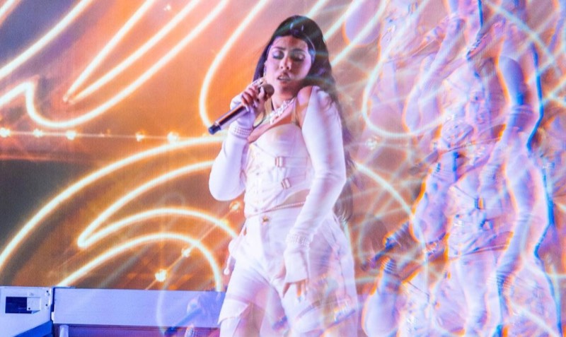 A singer in white under a wash of stage light