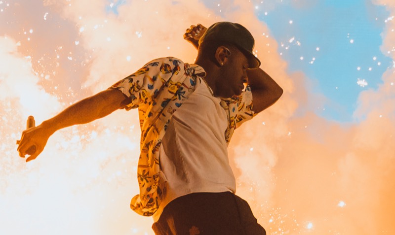 A performer leaping on stage against a bright sky
