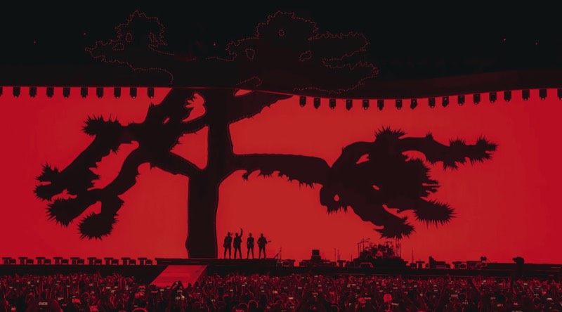 A red stage screen above a stadium crowd