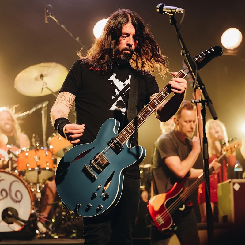 A guitarist singing on stage with his band