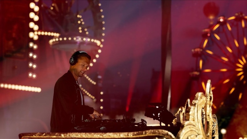 A DJ playing at a festival with a lit Ferris wheel behind